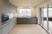 Vue de la cuisine avec plafond en bois apparent (photos : ©kämpfen für architektur ag, Zurich)
